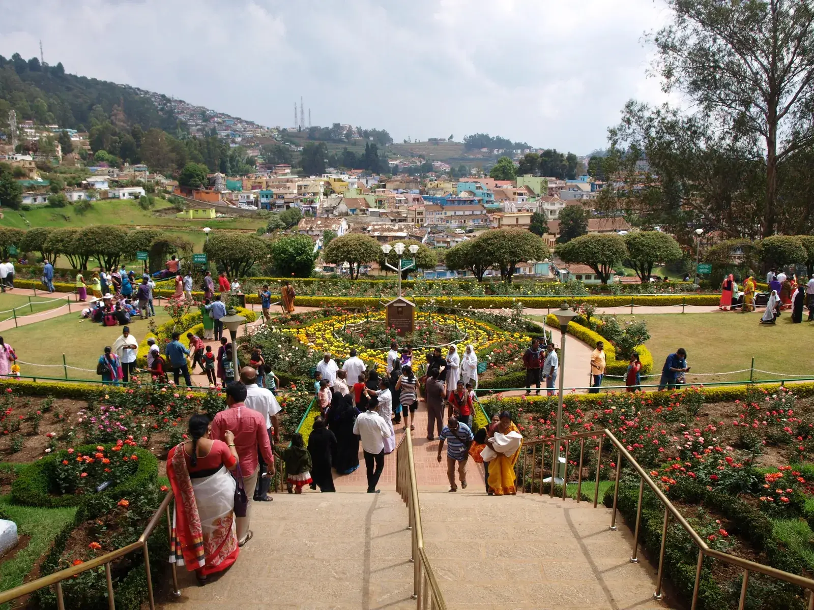 Families walking among flower beds at the Rose Garden in Ooty